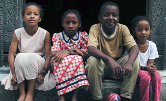Four Tanzanian children sit together on a step