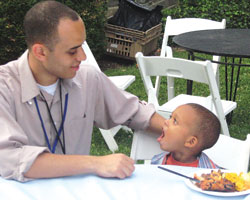 Photo: Dr. Gerald Bloomfield seated next to a 3-year-old boy at a picnic table
