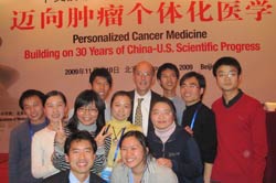 PHOTO: A large group of 11 smiling Chinese researchers, a mixture of men and women, stand around Dr. Roger Glass