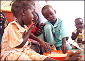 PHOTO: a girl and boy child eat with their hands from a large bowl