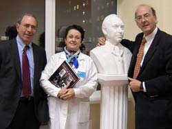 Dr. John I. Gallin, Prof. Elena N. Baibaraina and Dr Roger Glass stand together, Dr. Glass with his arm around a bust