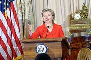 Photo: Hillary Rodham Clinton speaks from behind a podium, US flag to her right