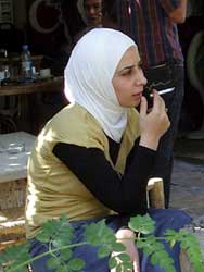 PHOTO: woman, seated, with head scarf, smokes ciagrette