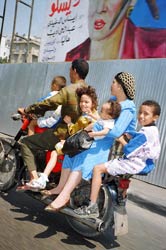 PHOTO: family of father, mother, and four children ride on a small scooter
