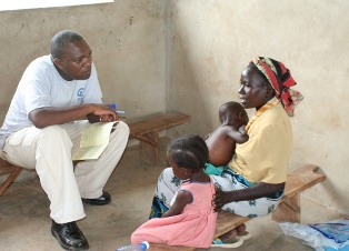 A man counsels a woman (with her two young children) about nutrition in Kenya.
