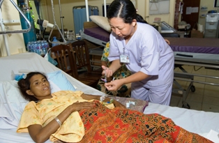 A nurse delivers medication to a patient at a Cambodian hospital. Photo credit: David Snyder