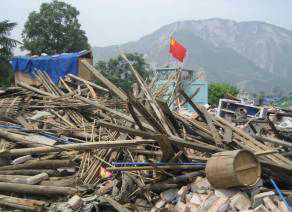a picture of destroyed buildings in China with Chinese flag sticking out of the rubble. Photo by Ma Hong.