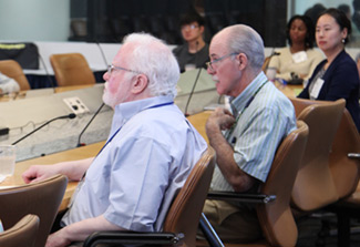 This photo shows Fogarty Deputy Director Peter Kilmarx (second from left) sitting at a table with colleagues. He is wearing glasses and a light shirt.