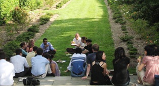 Fogarty scholars sitting down on the stairs and grounds of the Stone House gardens at their BBQ.