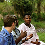 The photo shows three people sitting outside engaging in a discussion.